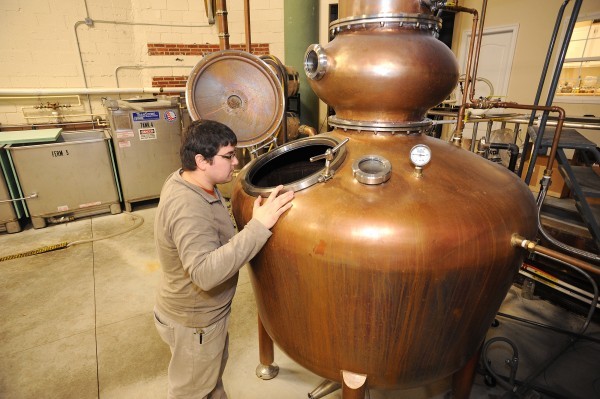 Painted Stave co-owner Mike Rasmussen looks into a copper pot still in the distillery in Smyrna.